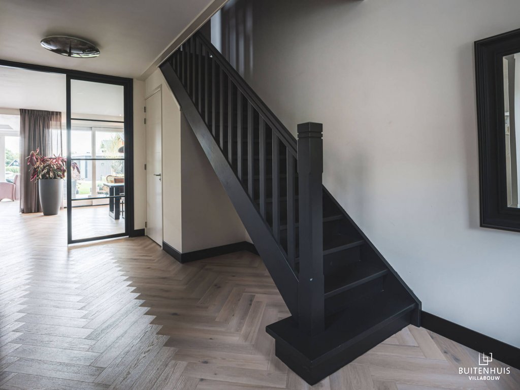 ThumbnailStijlvolle zwarte houten trap die contrasteert met de lichte visgraat vloer
