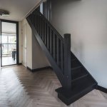 ThumbnailStijlvolle zwarte houten trap die contrasteert met de lichte visgraat vloer