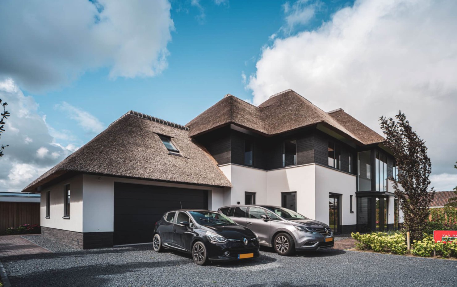 Voorgevel landhuis met rieten kap gezien vanaf de garage