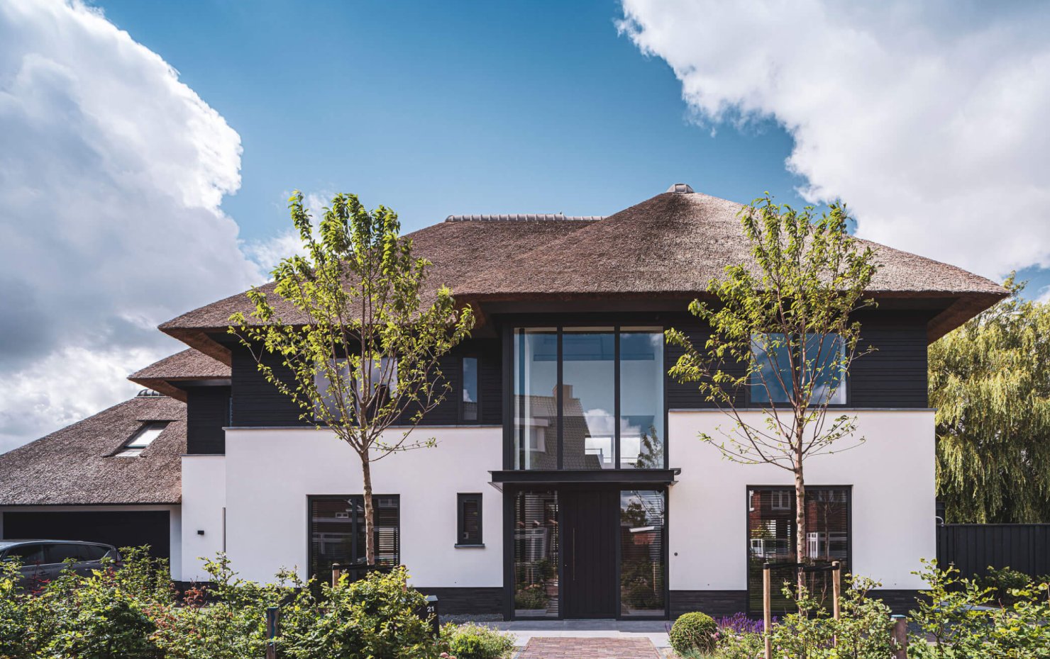 Entree landhuis met glazen gevel tot aan de rieten kap