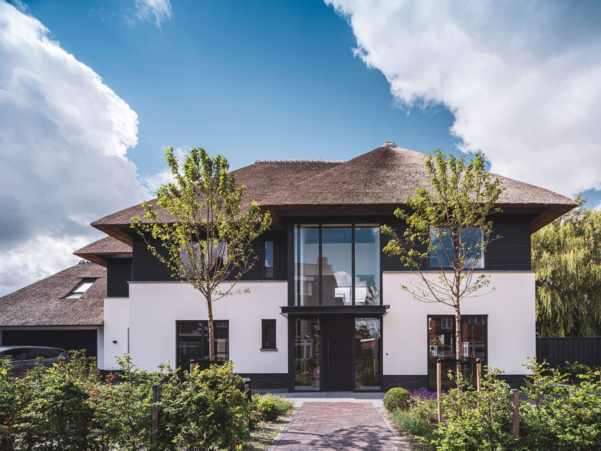 Entree landhuis met glazen gevel tot aan de rieten kap