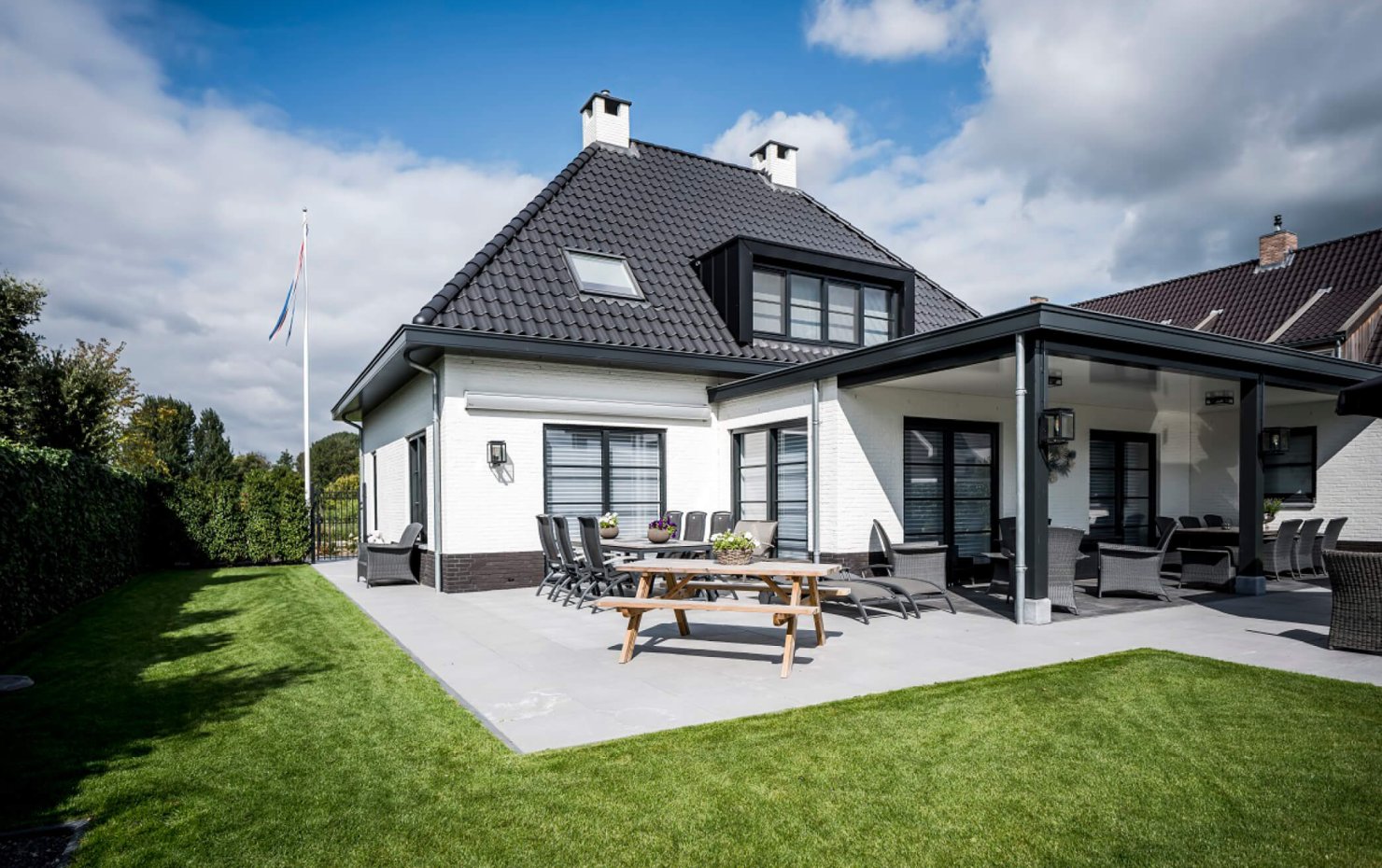 Achtergevel en zijgevel van een klassiek herenhuis met openslaande tuindeuren en veranda