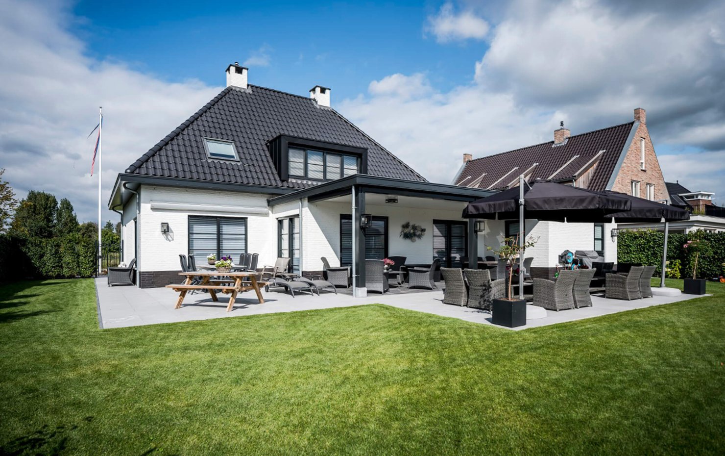 Achterzijde landelijke notariswoning met beschutte zithoek onder de diepe veranda en naast de garage