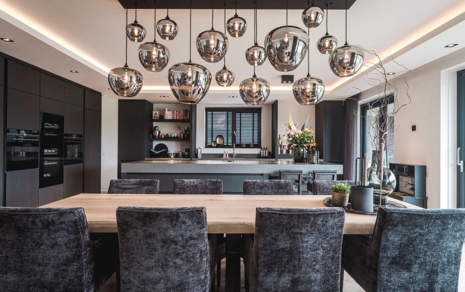 Glazen designlampen boven de robuuste houten eettafel