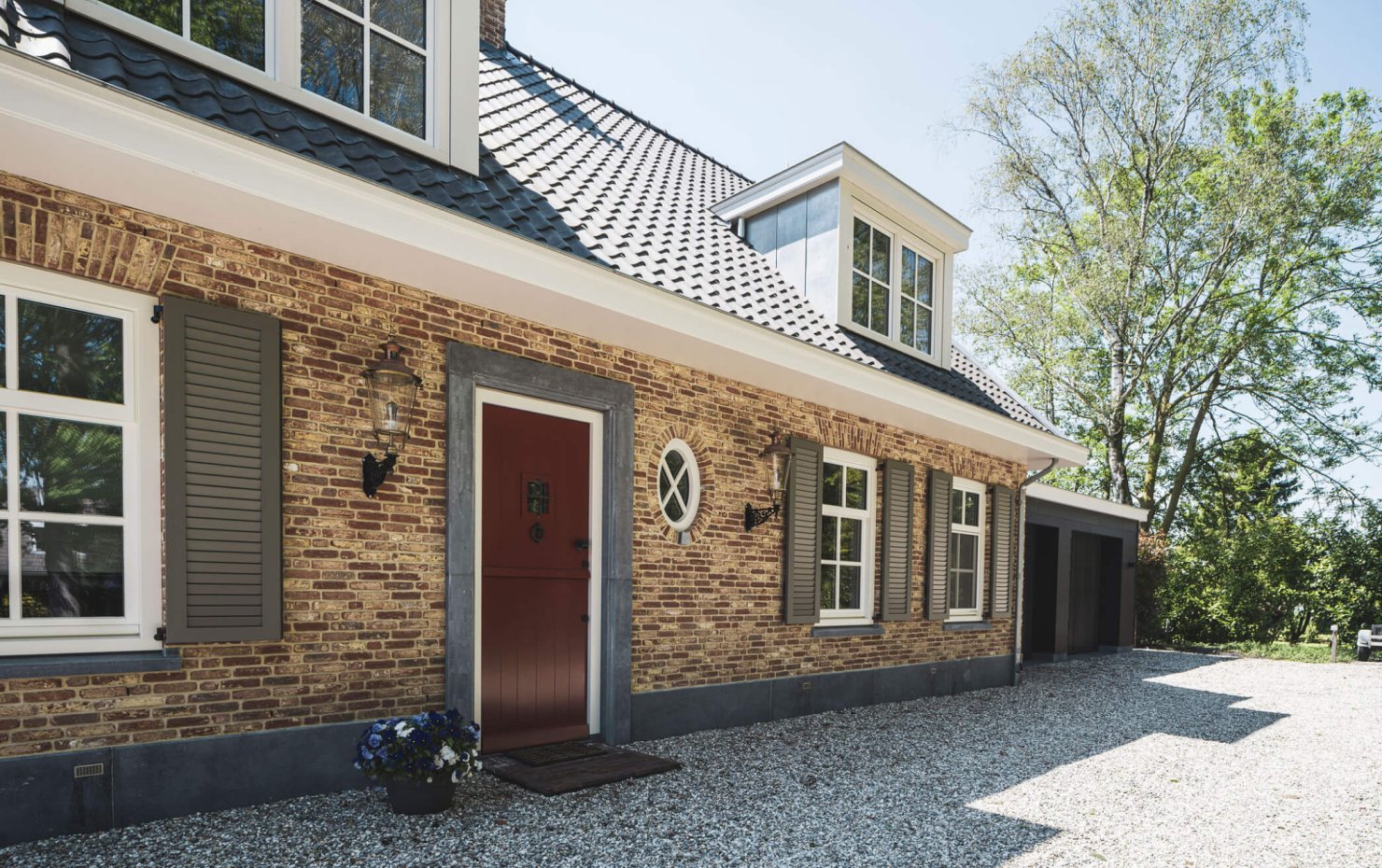 Voordeur met natuurstenen omlijsting, naast rond raam in de gevel