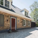 ThumbnailVoordeur met natuurstenen omlijsting, naast rond raam in de gevel