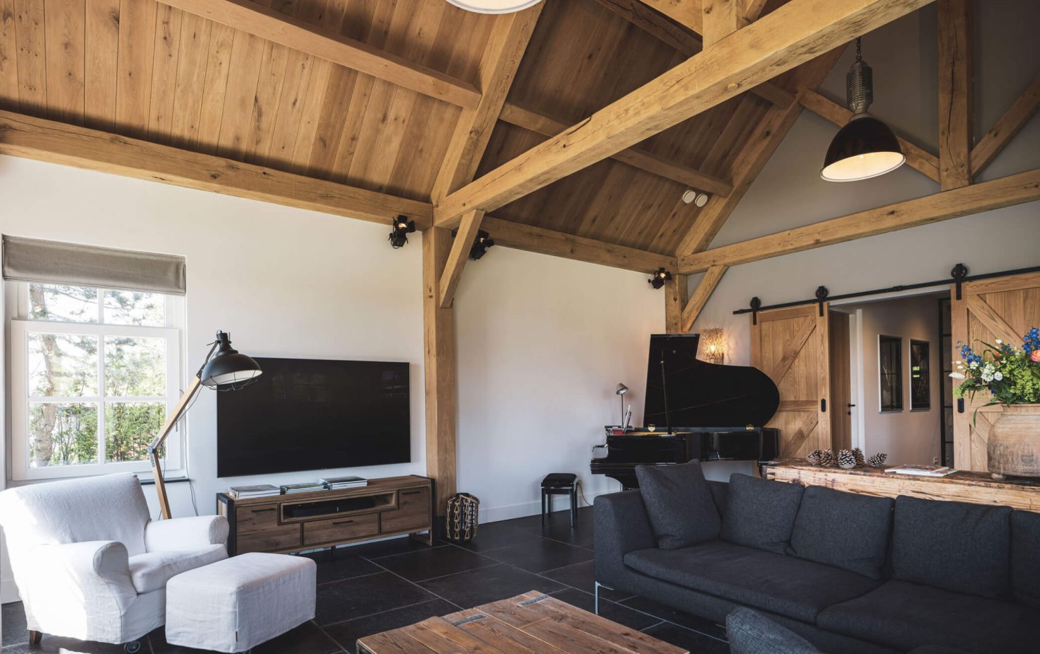 Interieur met houten plafiod en eiken balkenconstructie en stoere staldeuren