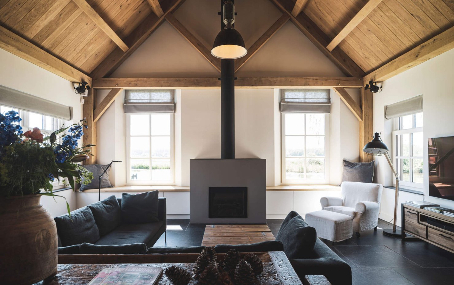 Interieur met eiken balken en houten plafiond, op de vloer grote natuurstenen tegels