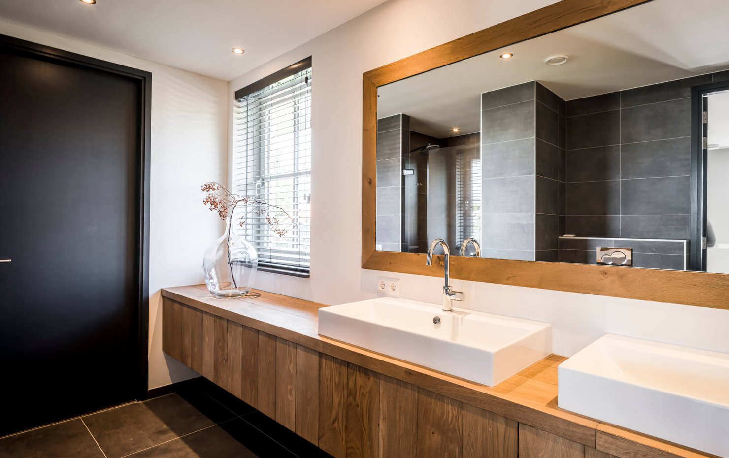 Design badkamer met zwevende houten kast en zwarte vloertegels en wandtegels