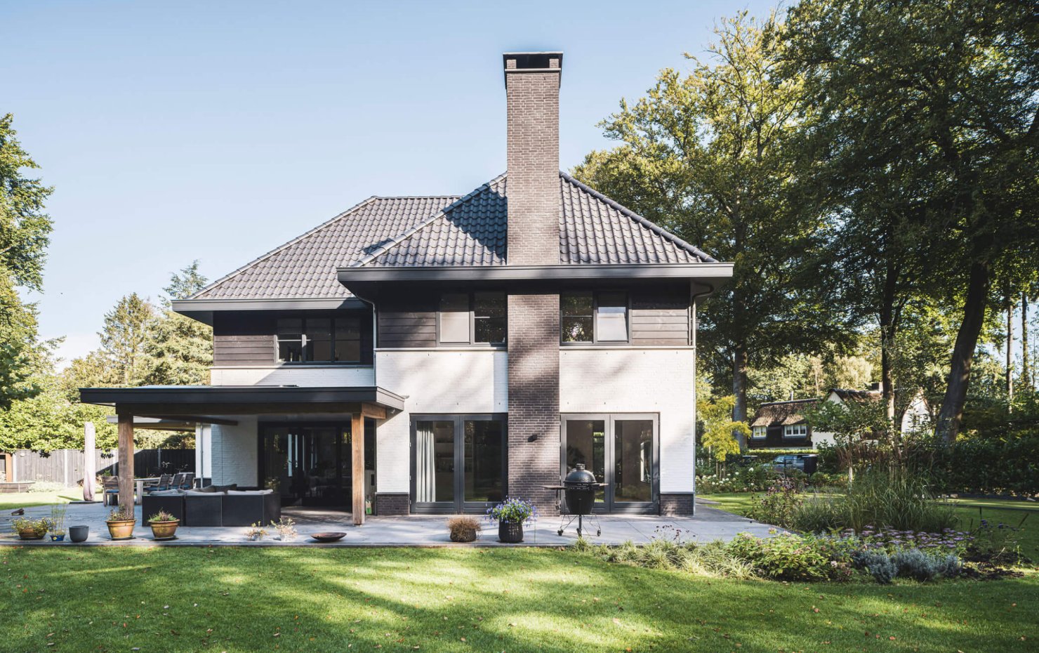 Zijgevel jaren-30-villa met markante schoorsteen in donkere baksteen