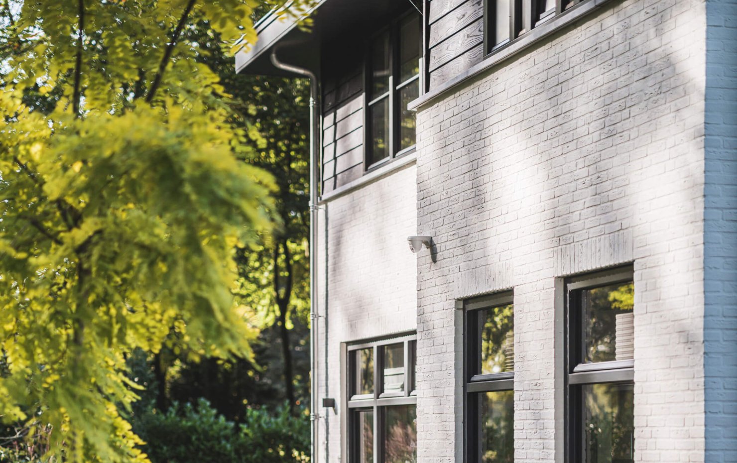 Zwarte potdeksel op de zijgevel van een jaren-30-villa