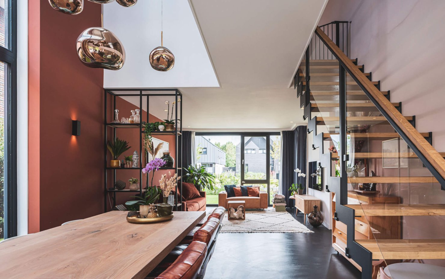 Living met strakke gietvloer en stoeren houten trap met staal en glas