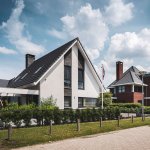 ThumbnailModerne woning met witte gevel, donkere baksteen accenten en zonneterras met lamellen