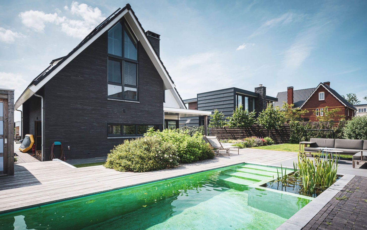 Zwemvijver met natuurlijke filtering en houten buitenparket eromheen