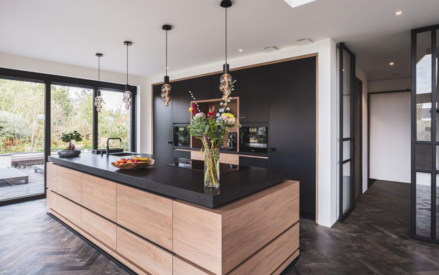 Zwarte design keuken met kookeiland en houten greeploze kastdeuren