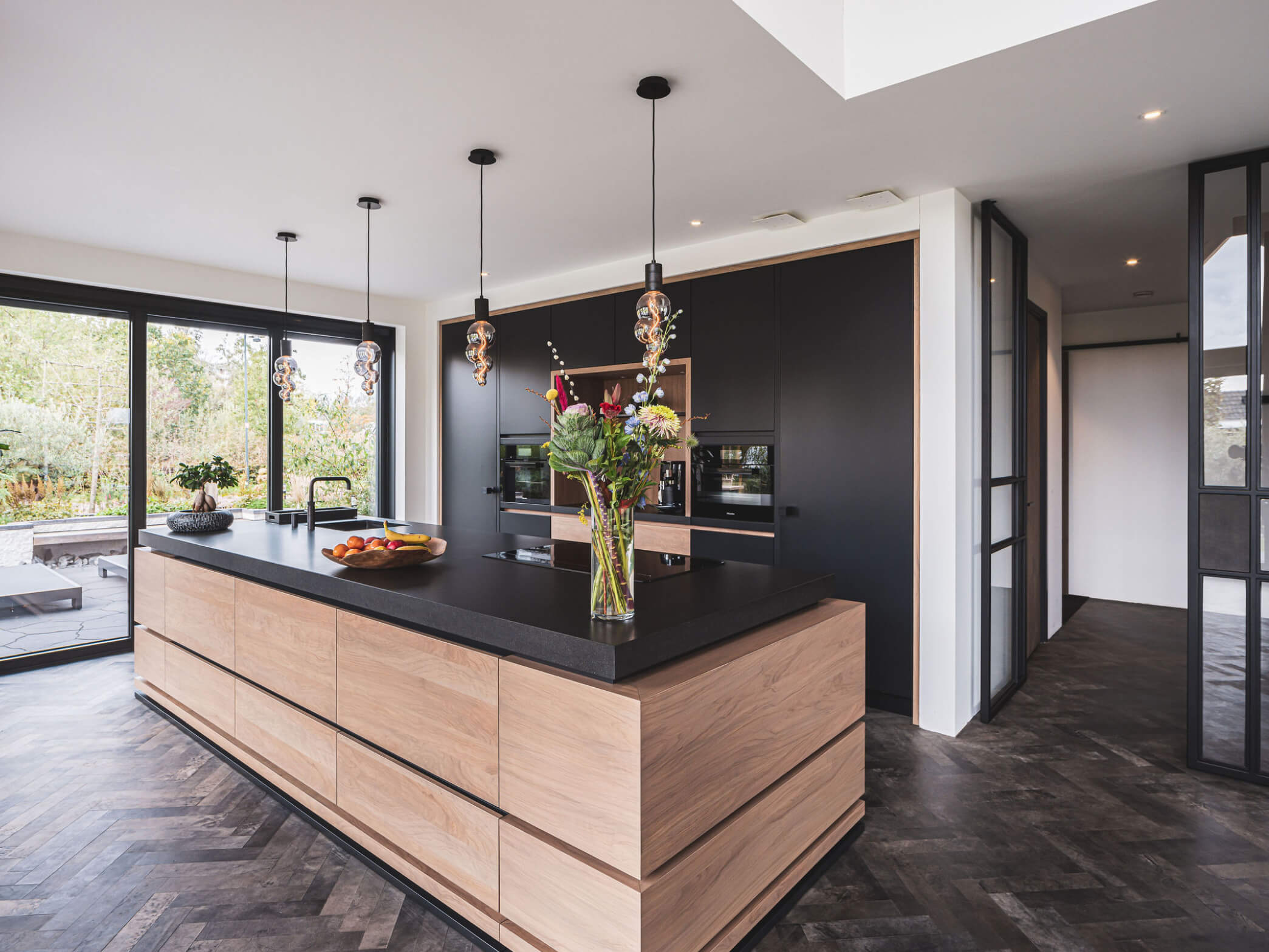 Zwarte design keuken met kookeiland en houten greeploze kastdeuren