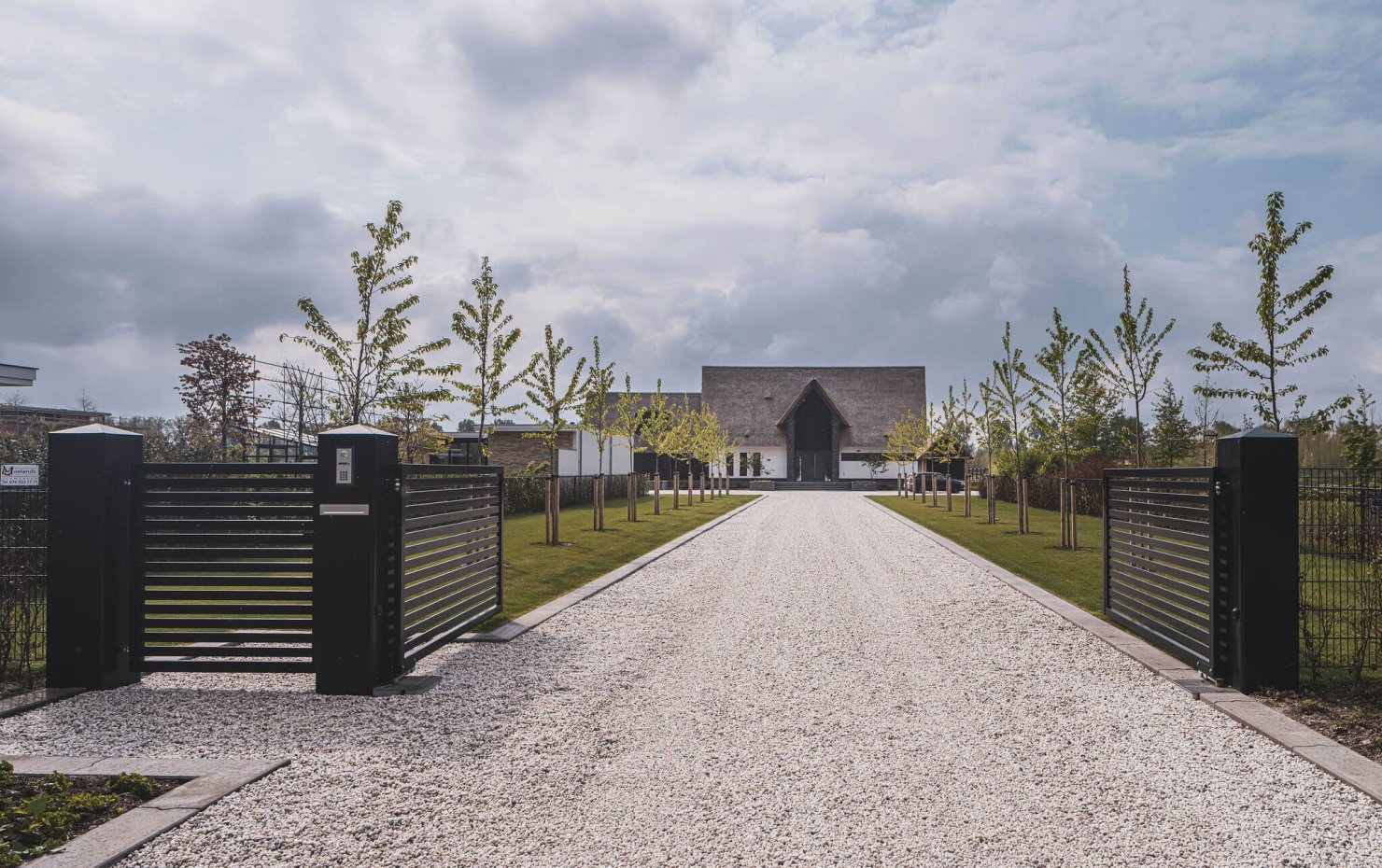 Lange oprit bij landhuis met rieten kap