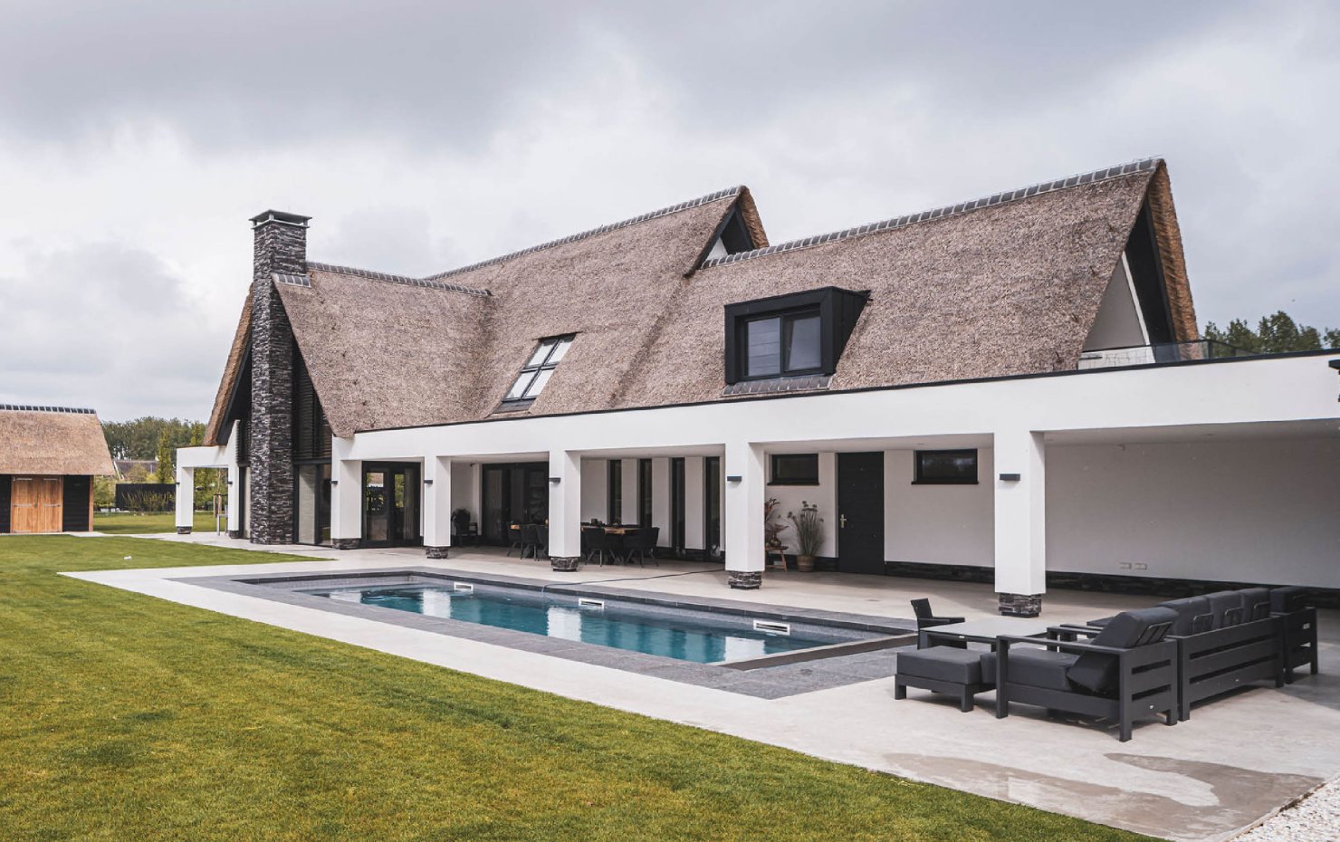 Achtergevel landhuis met rieten kap en witte overkapping