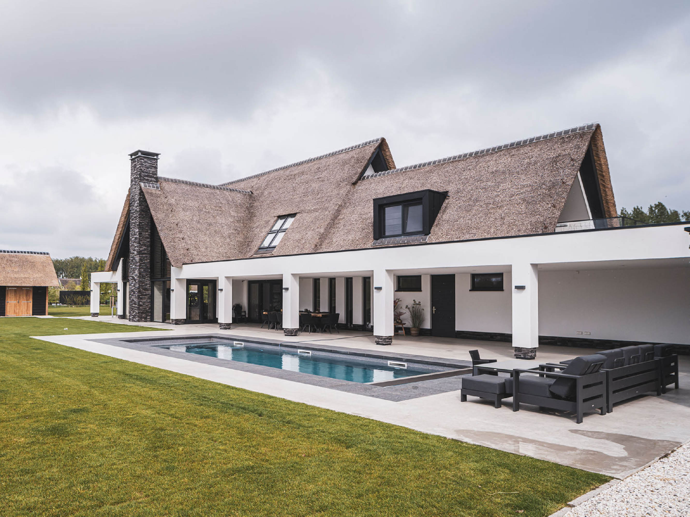 Achtergevel landhuis met rieten kap en witte overkapping