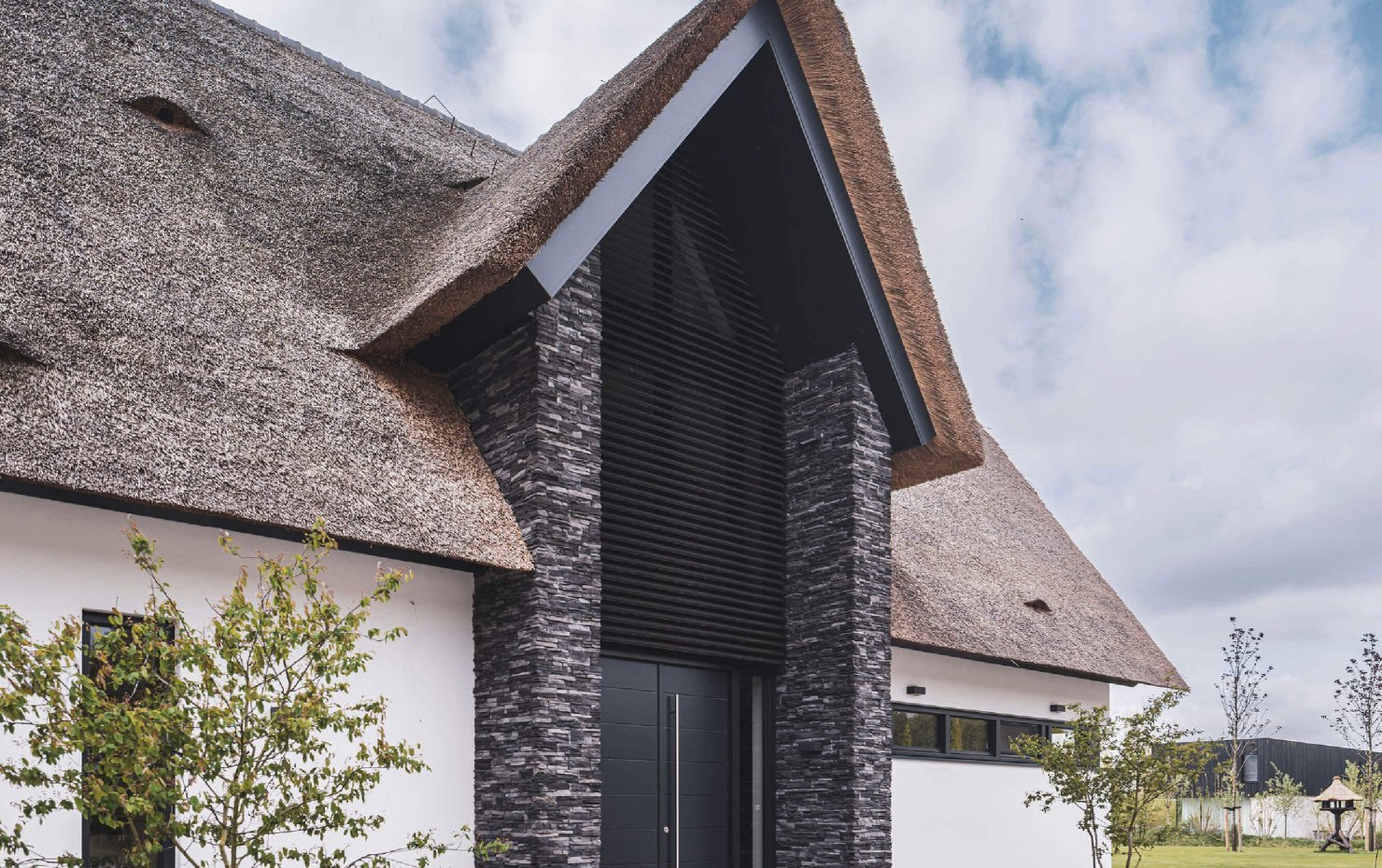 Indrukwekkende entree van villa met rieten dak met bijzondere materialen