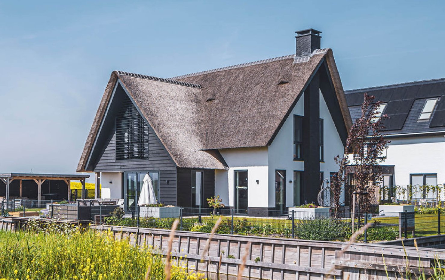 Aanzicht van een moderne villa met rieten dak aan het water