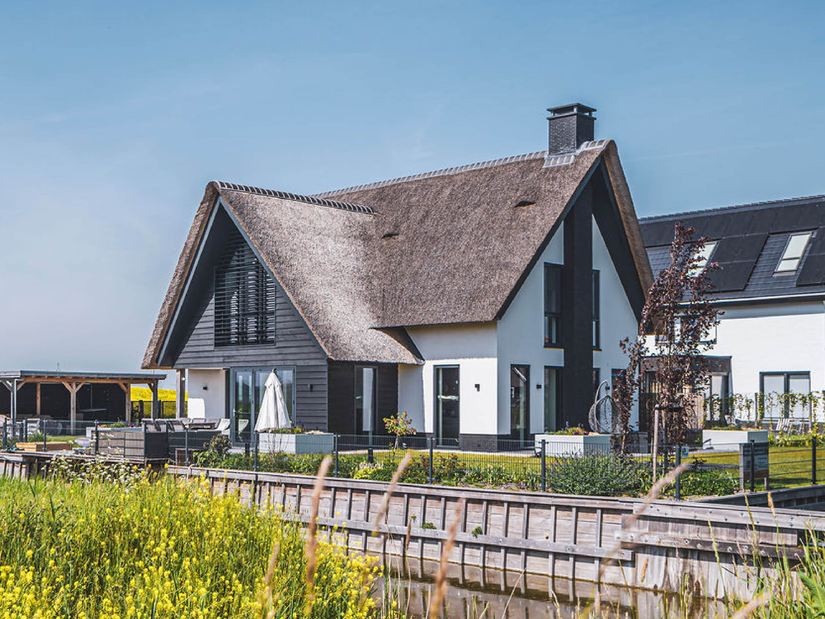 Aanzicht van een moderne villa met rieten dak aan het water