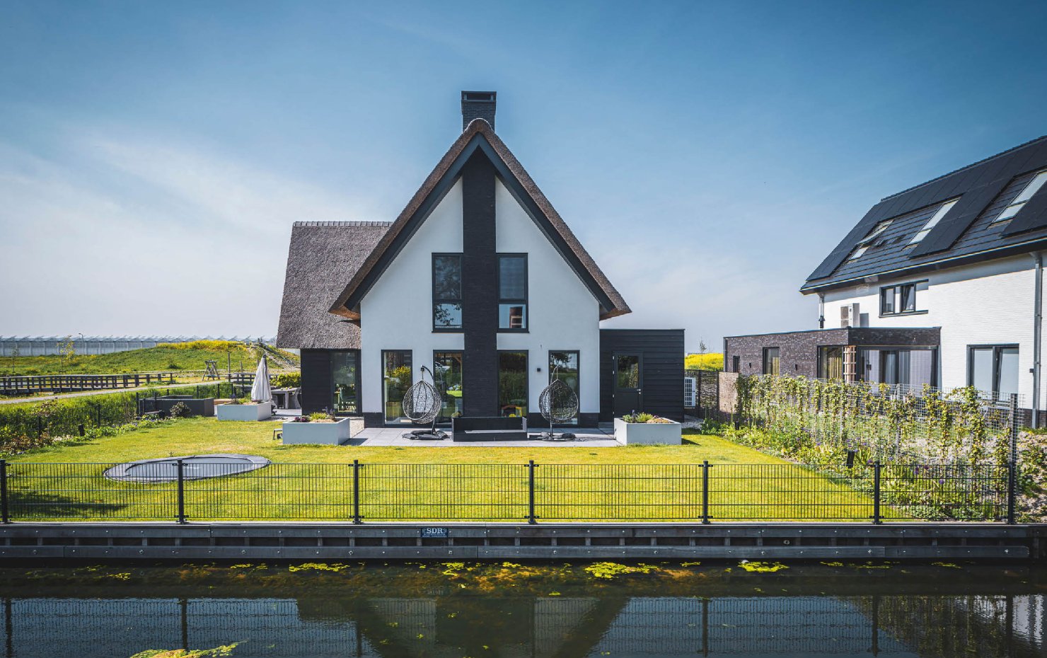 Aanzicht vanaf het water van en moderne villa met rieten kap