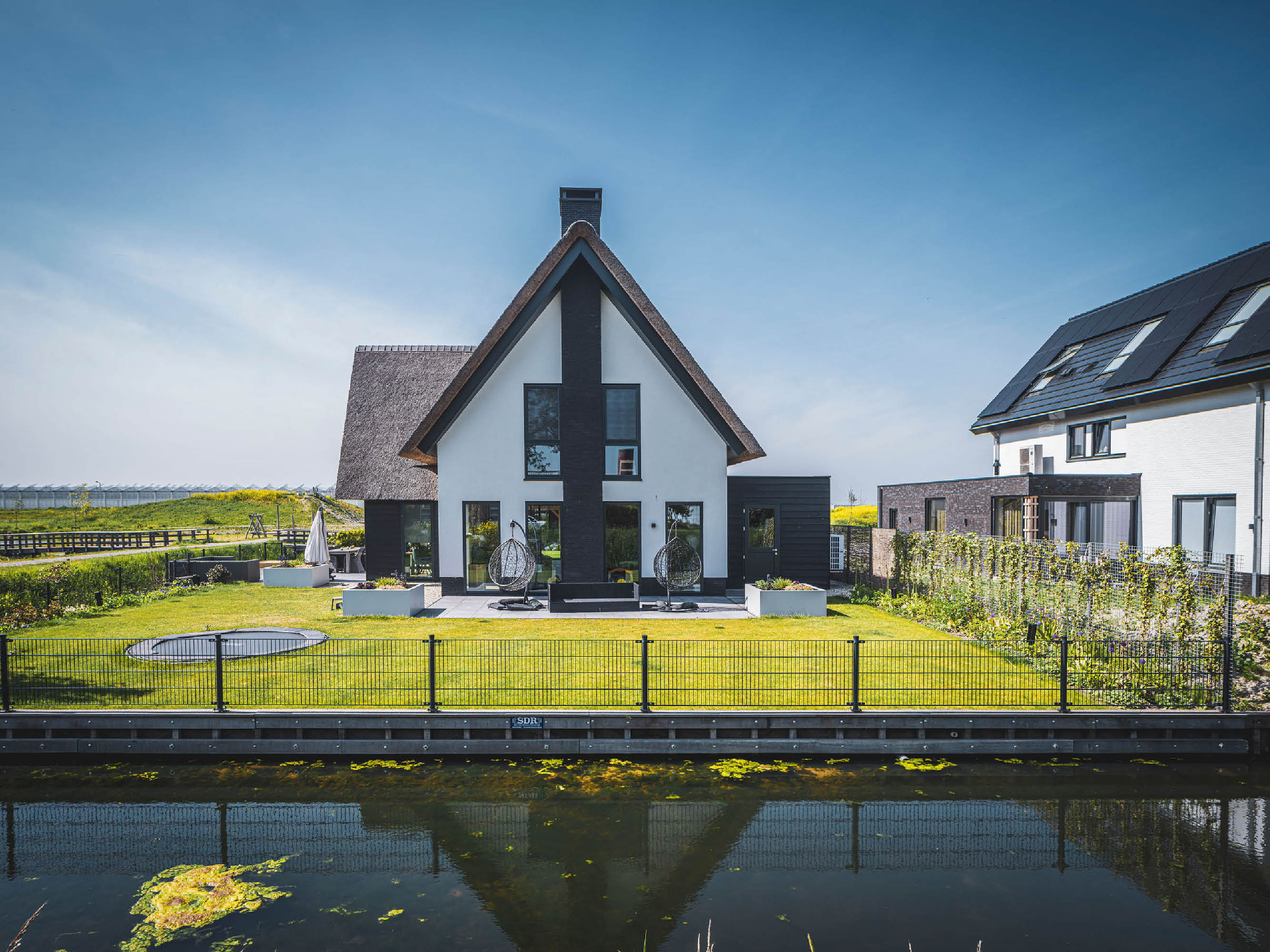 Aanzicht vanaf het water van en moderne villa met rieten kap