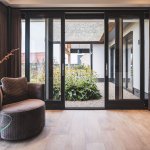 ThumbnailModern warm interieur met zwarte openstaande schuifpui