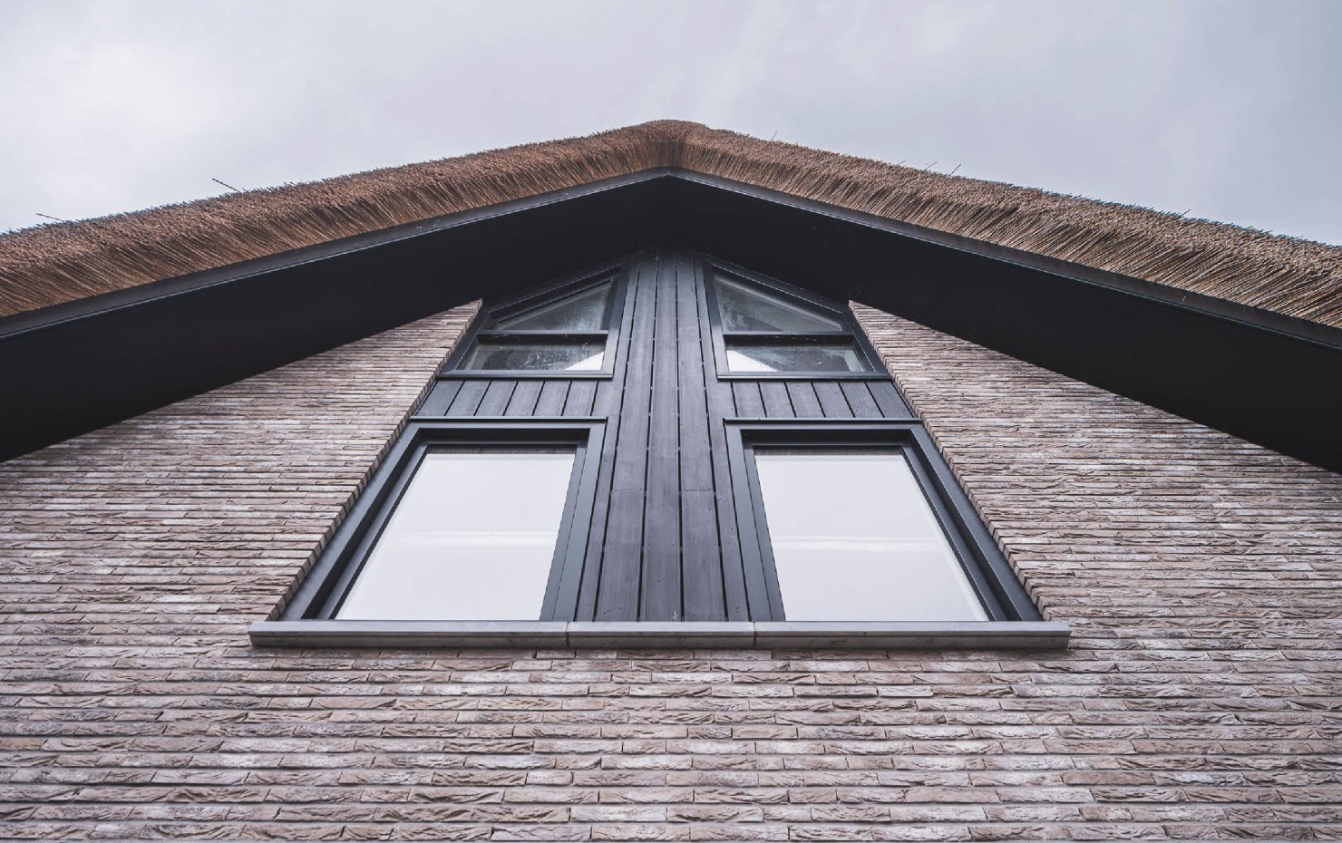Gevelbeeld van een moderne villa met rieten kap en zonwering