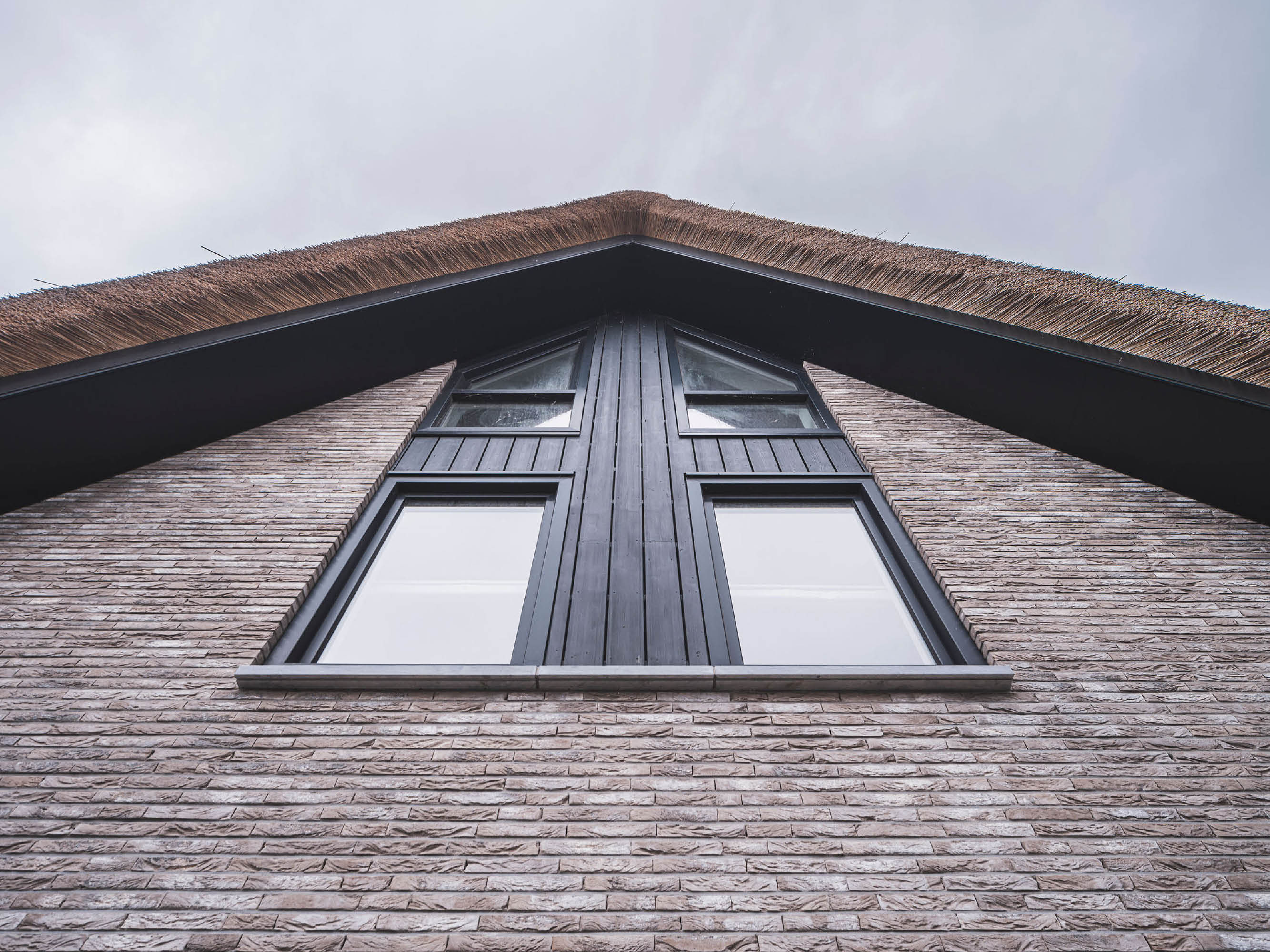 Gevelbeeld van een moderne villa met rieten kap en zonwering