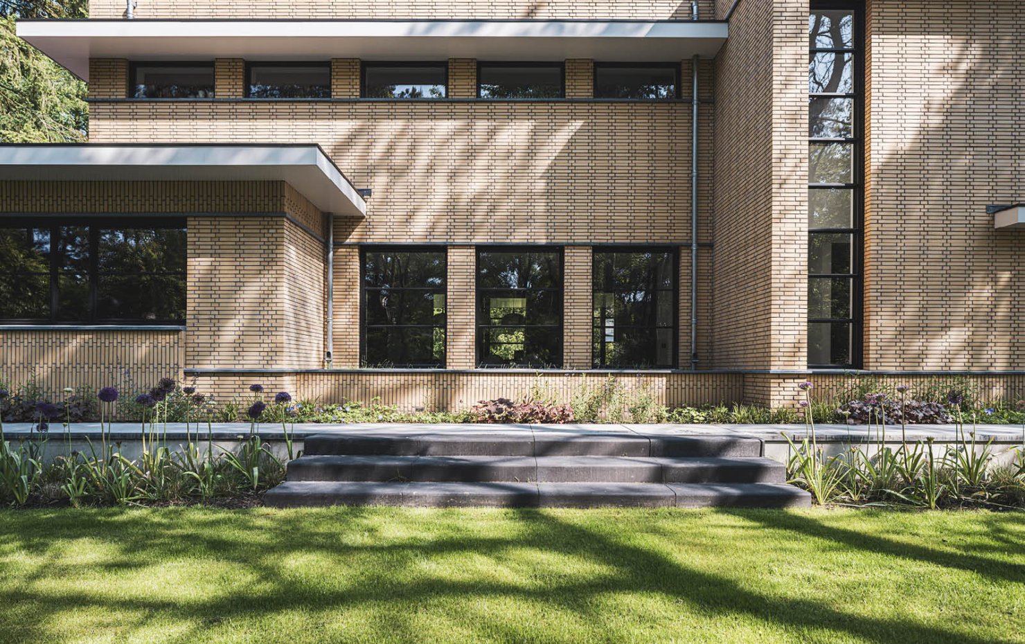 Villa in Dokukstijl met grote ramen, plantenborders en trapje