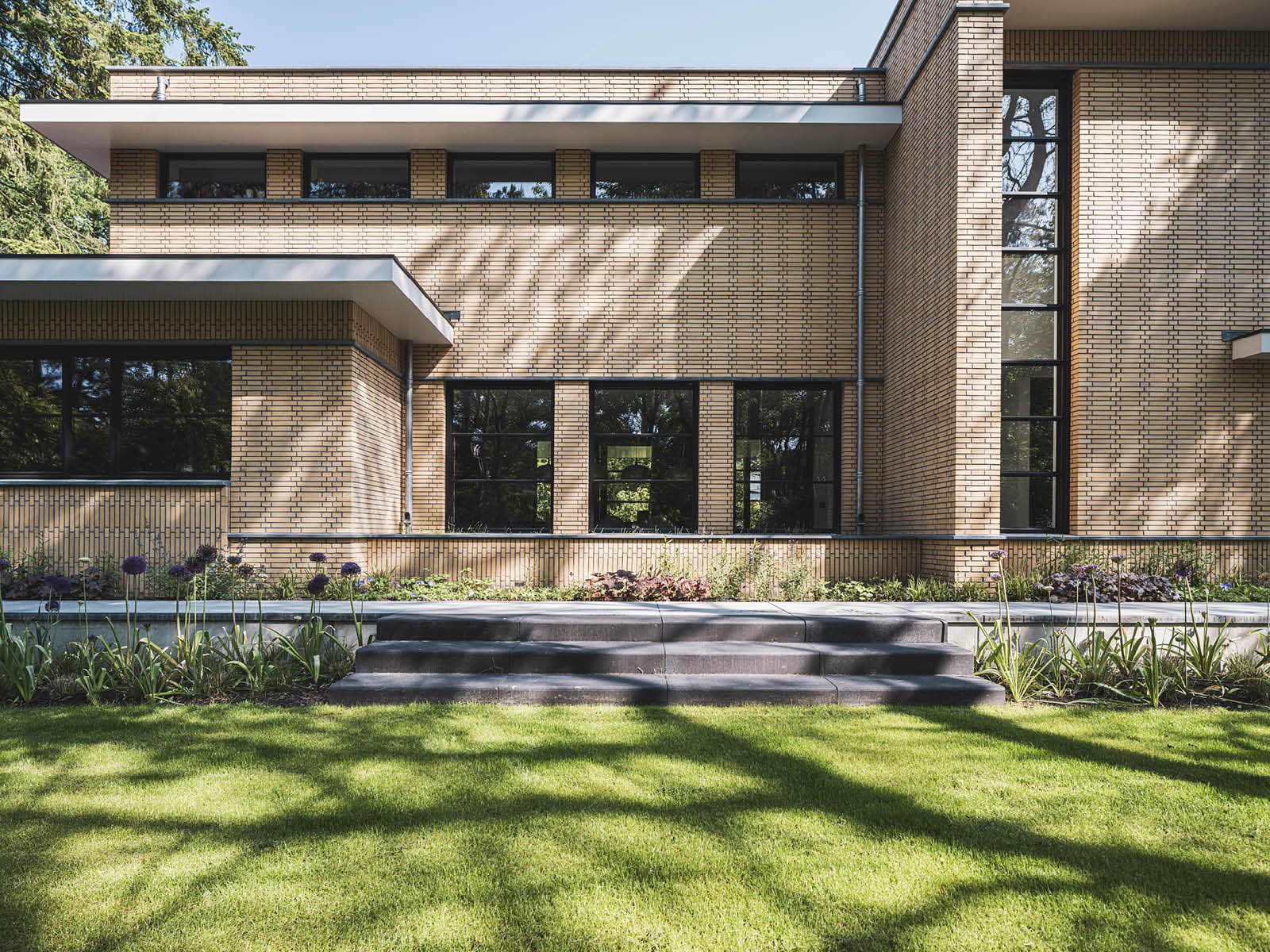 Villa in Dokukstijl met grote ramen, plantenborders en trapje