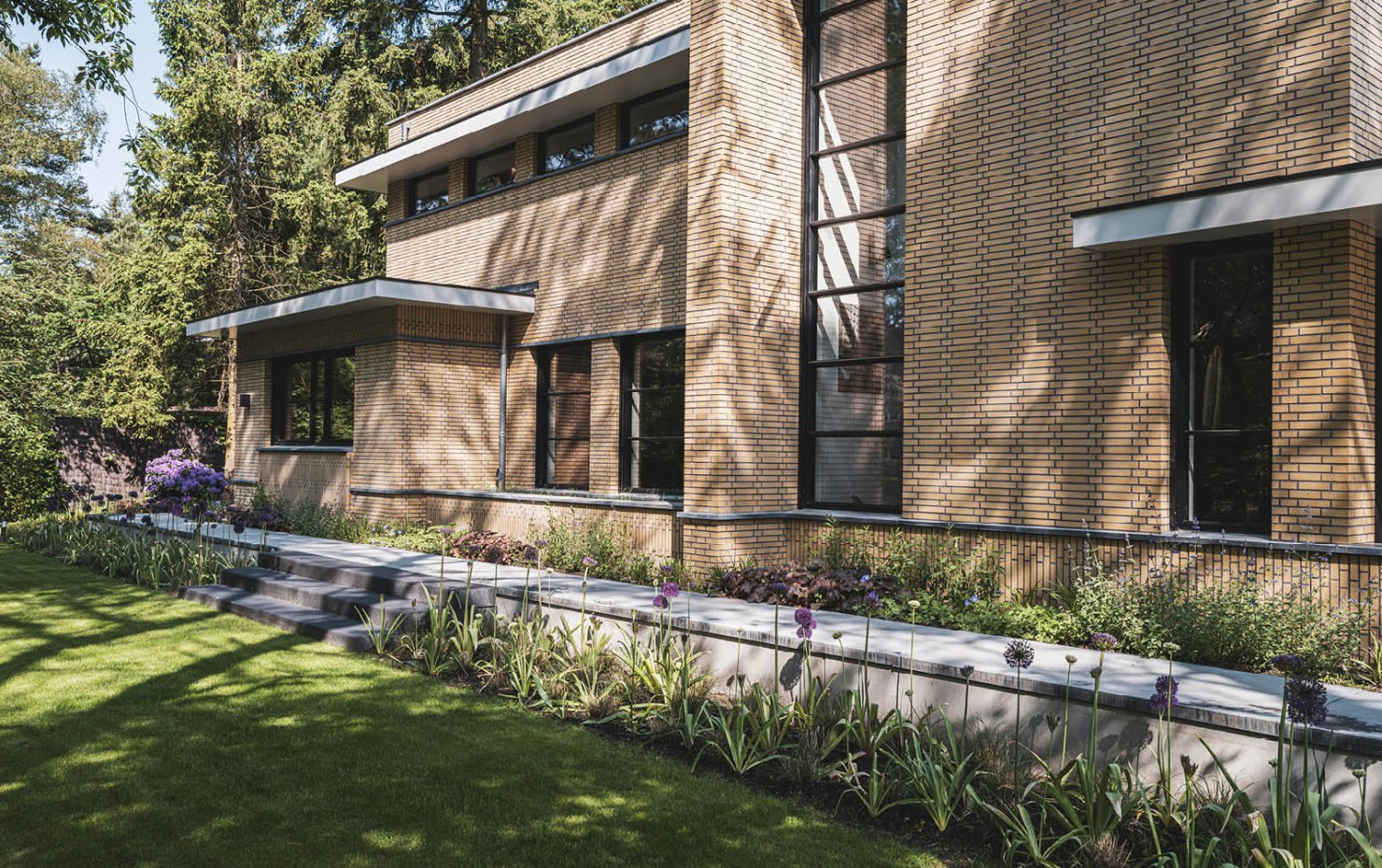 Villa in Dokukstijl met grote ramen, plantenborders en trapje