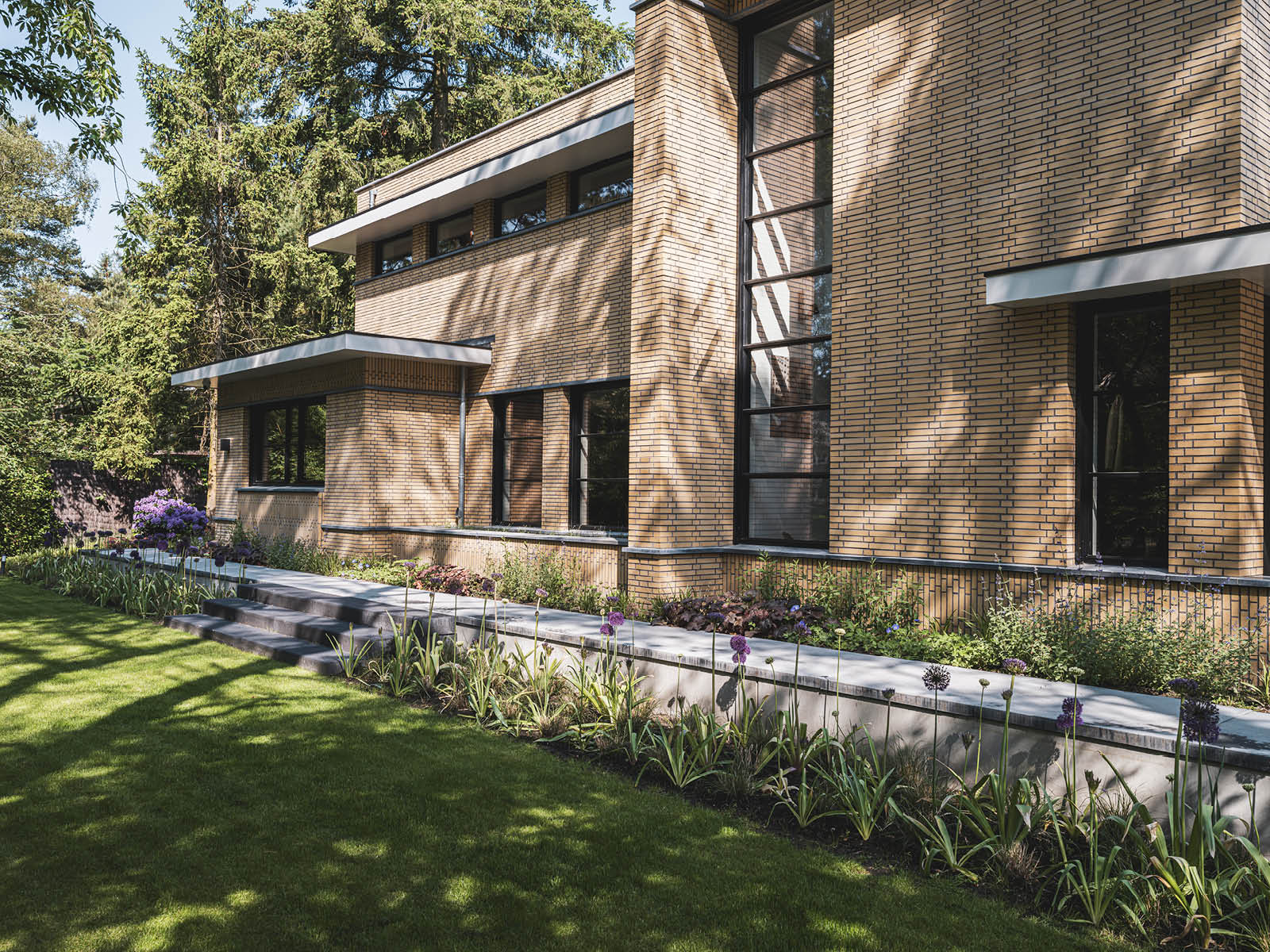 Villa in Dokukstijl met grote ramen, plantenborders en trapje