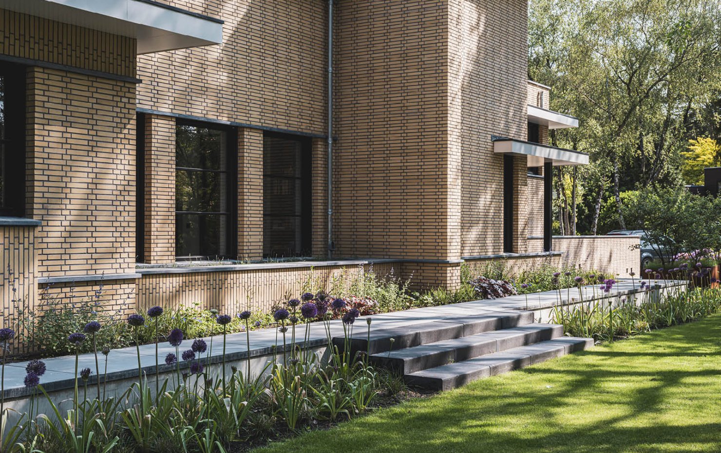 Villa in Dokukstijl met grote ramen, plantenborders en trapje