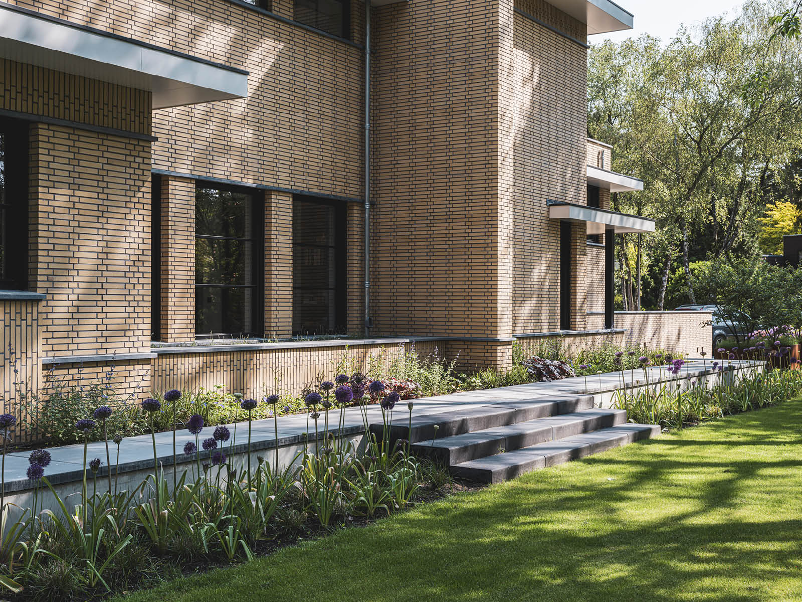 Villa in Dokukstijl met grote ramen, plantenborders en trapje