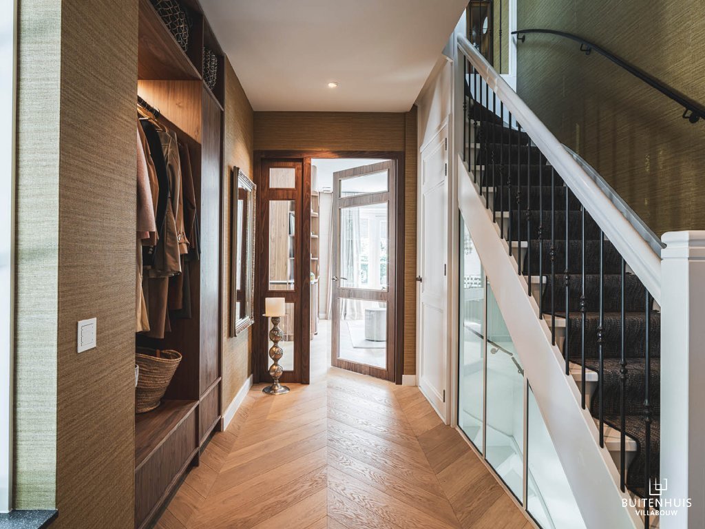 ThumbnailGang met ingebouwde garderobe, witte trap en glazen deuren naar de woonkamer