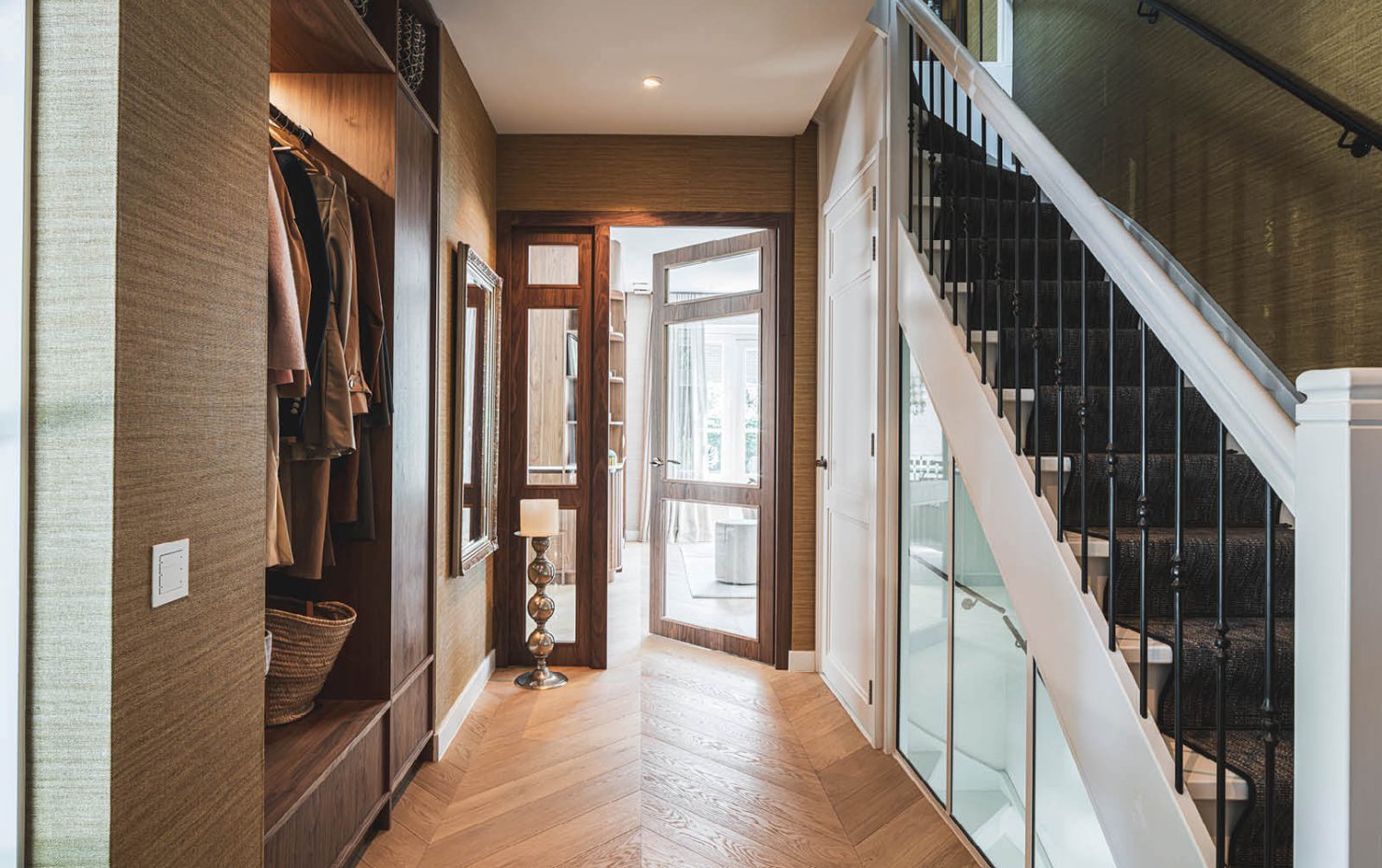 Gang met ingebouwde garderobe, witte trap en glazen deuren naar de woonkamer