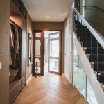 ThumbnailGang met ingebouwde garderobe, witte trap en glazen deuren naar de woonkamer