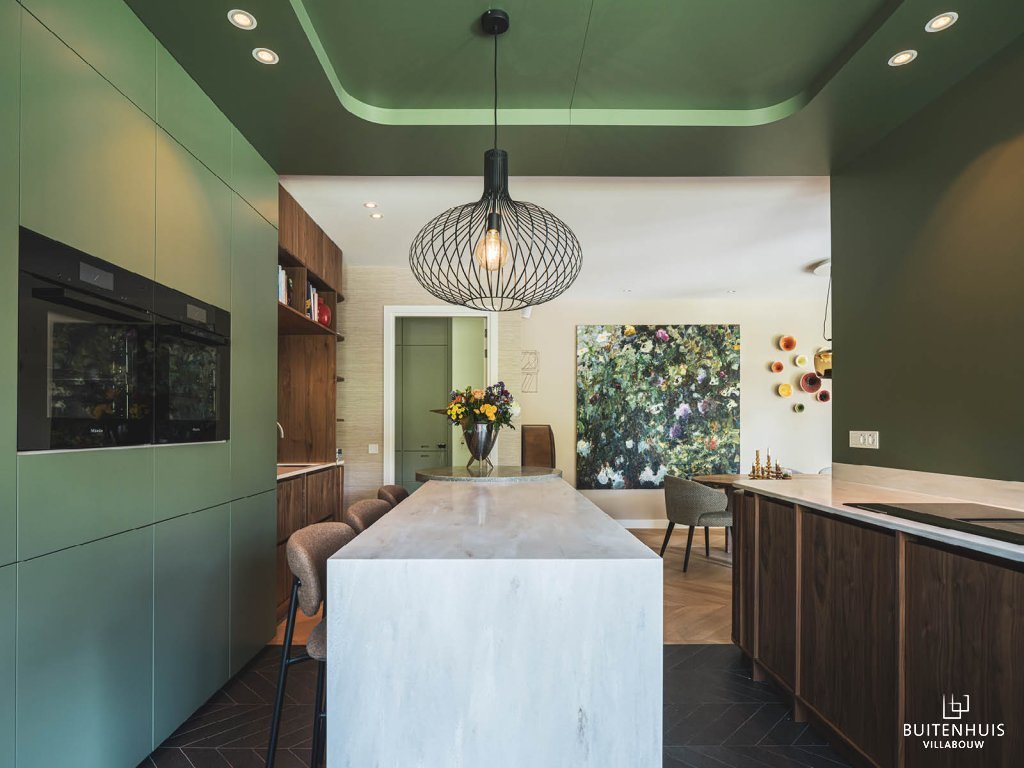 ThumbnailGroene keuken met hoge barretje, met op de achtergrond de eettafel