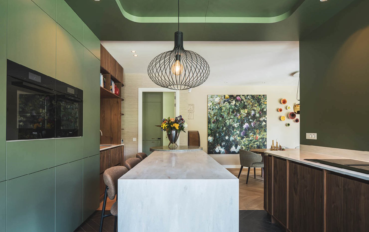 Groene keuken met hoge barretje, met op de achtergrond de eettafel