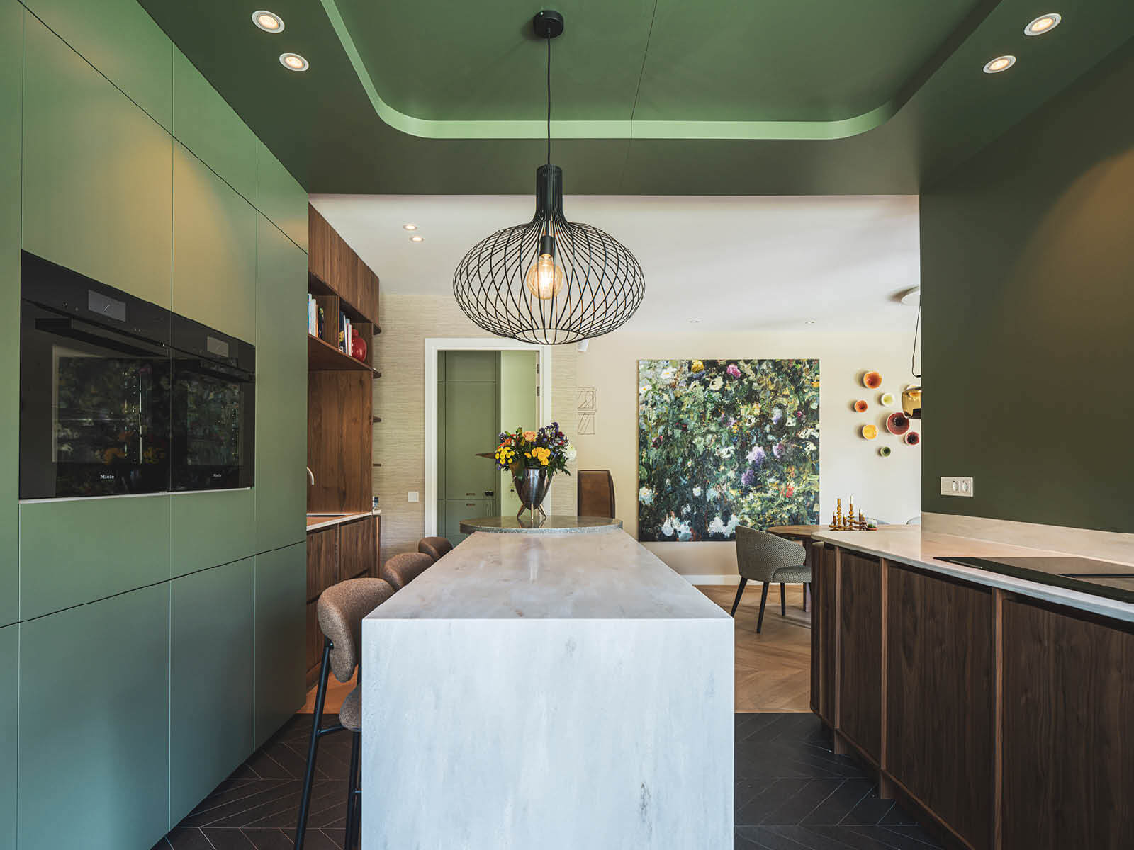 Groene keuken met hoge barretje, met op de achtergrond de eettafel