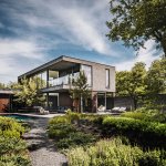 ThumbnailFotografie van een Buitenhuis Villabouw project, een modern huis met grijze houten gevel, zwembad, en houten terras.