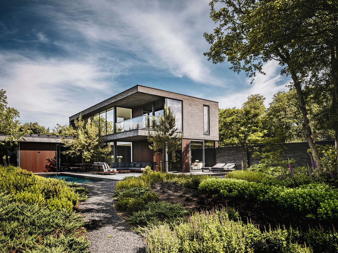 Fotografie van een Buitenhuis Villabouw project, een modern huis met grijze houten gevel, zwembad, en houten terras.