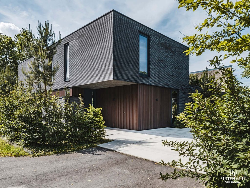 ThumbnailModerne kubistische villa met donkere houten gevel en opvallende vorm.