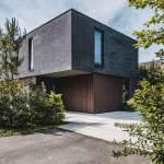 ThumbnailModerne kubistische villa met donkere houten gevel en opvallende vorm.