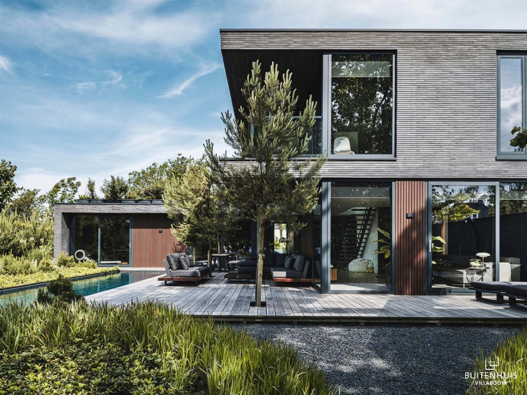 ThumbnailFoto van een luxe kubistische villa met een zwembad en houten terras, die het architectonisch ontwerp en de buitenruimte laat zien.