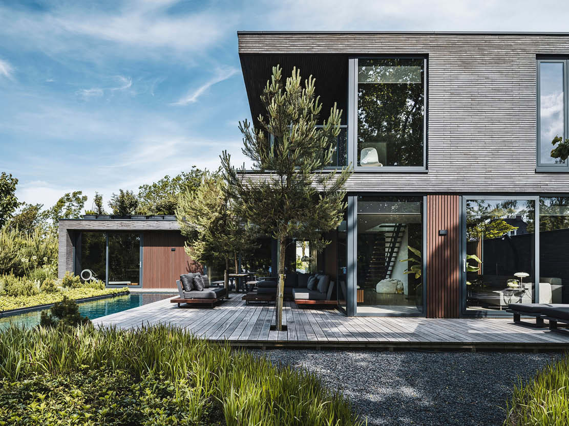 Foto van een luxe kubistische villa met een zwembad en houten terras, die het architectonisch ontwerp en de buitenruimte laat zien.